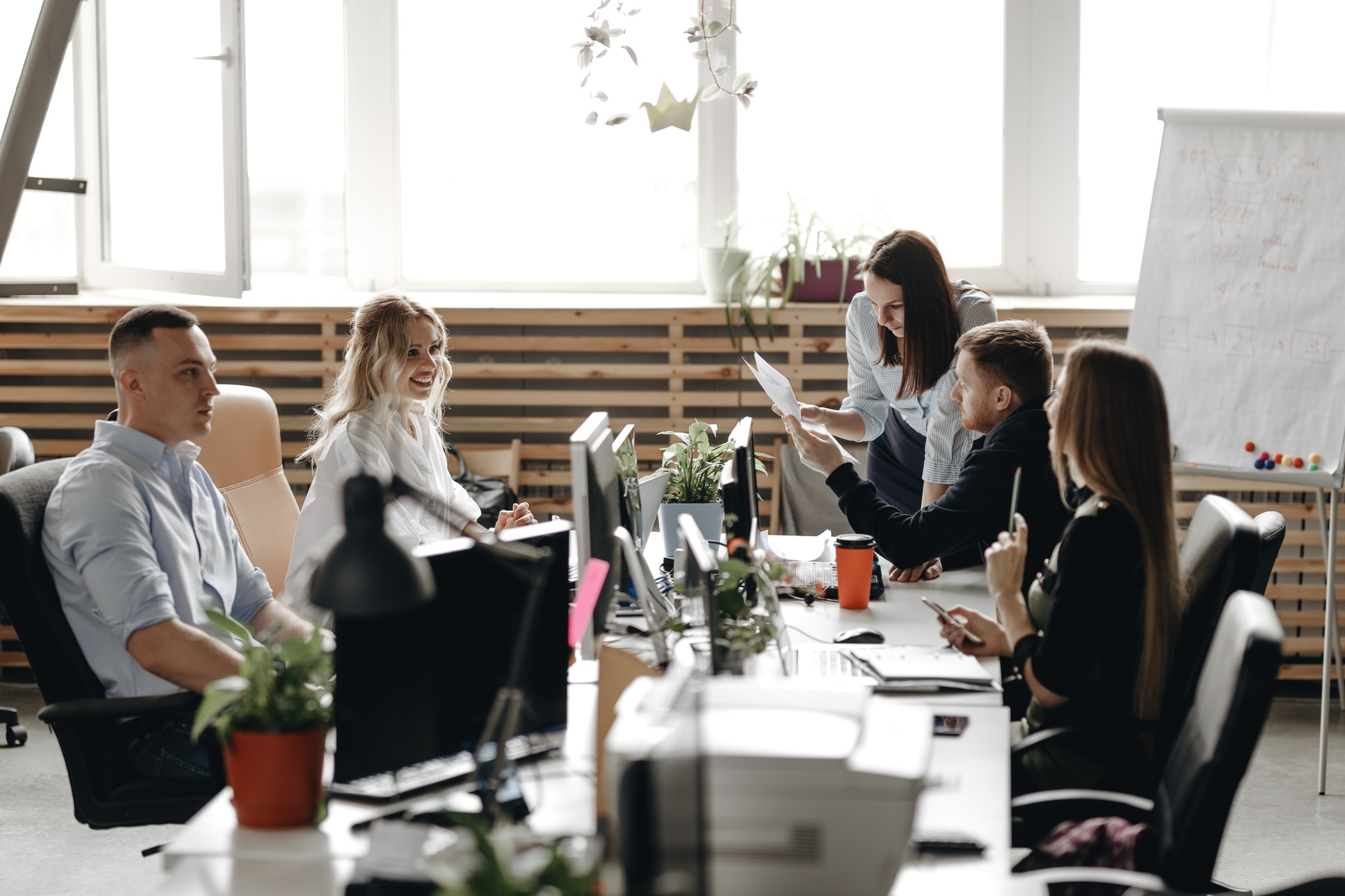 Staff meeting of a young successful team in the light modern office equipped with modern office