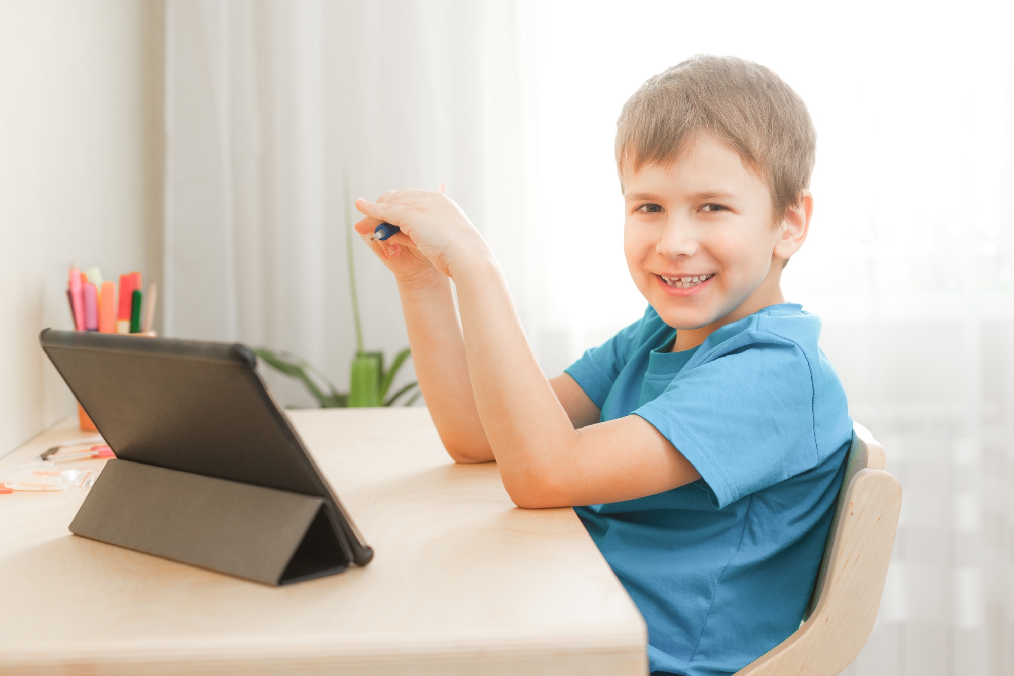 7 years old child boy doing lessons sitting at desk in his room.