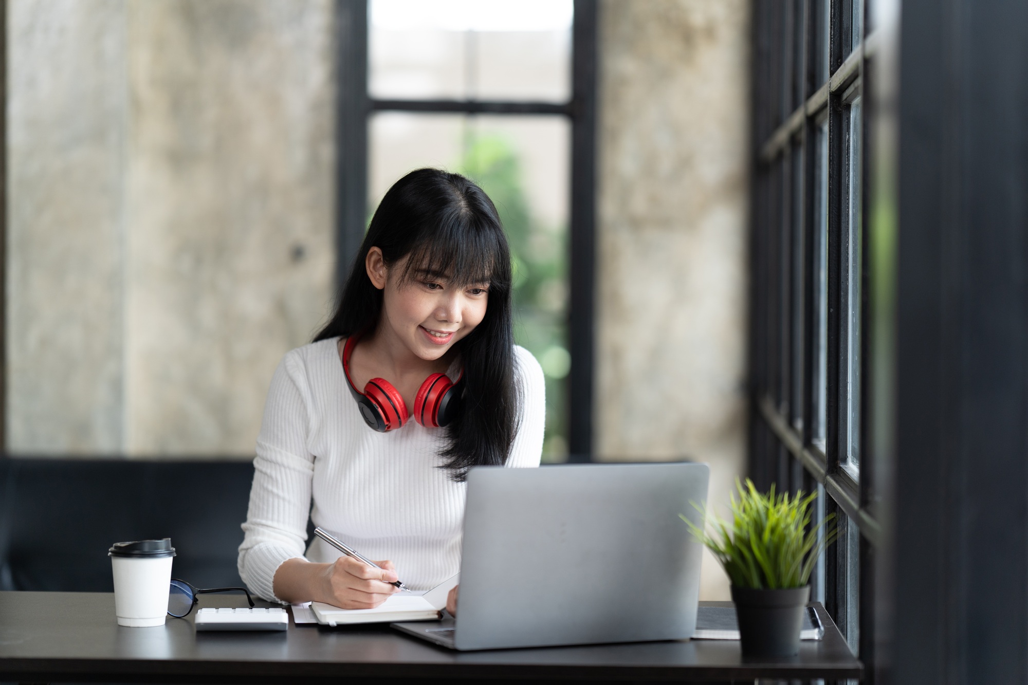 A young female student sitting at the table, using computer laptop when studying.