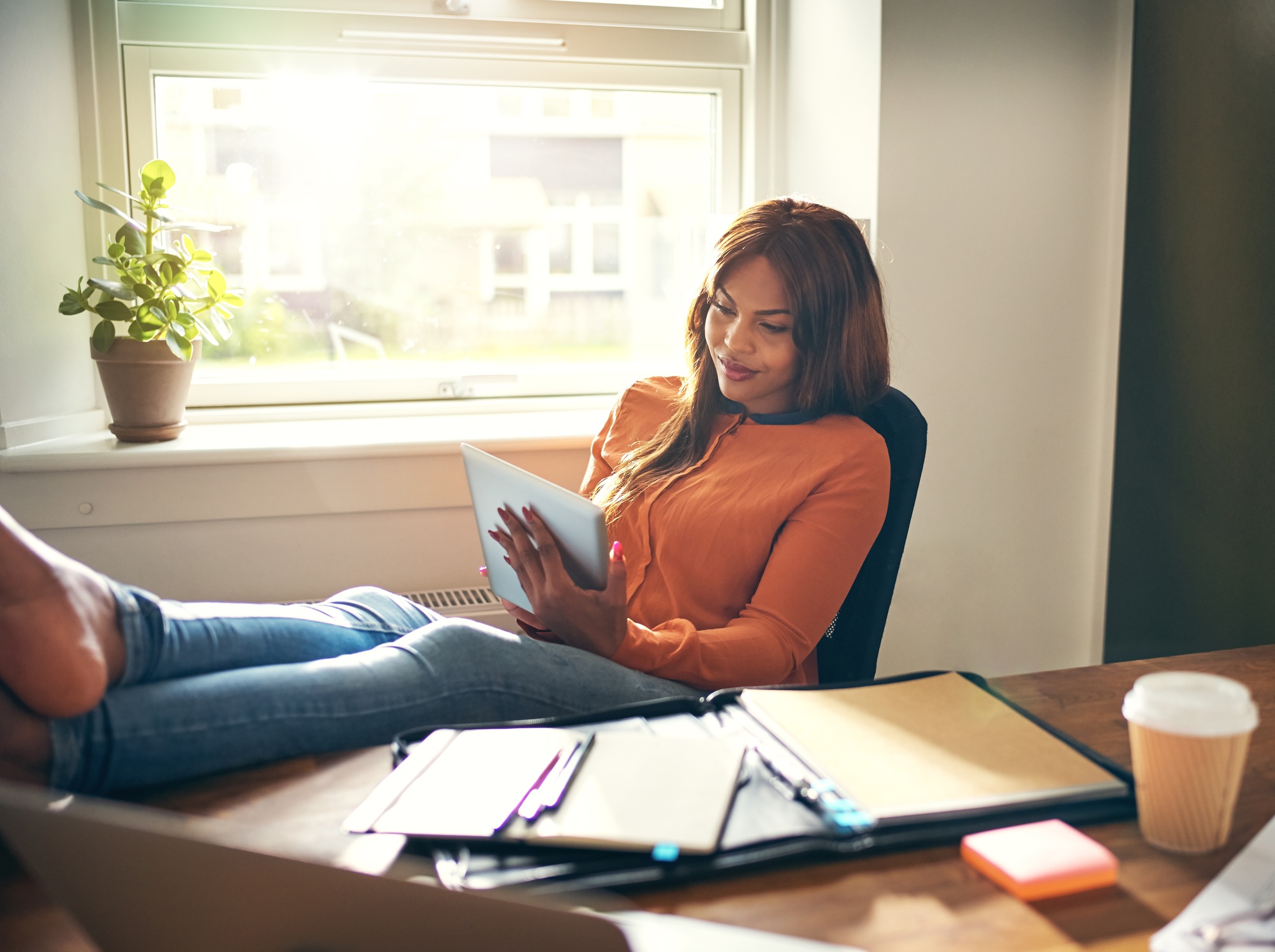 Smiling woman leaning back in her office chair working online