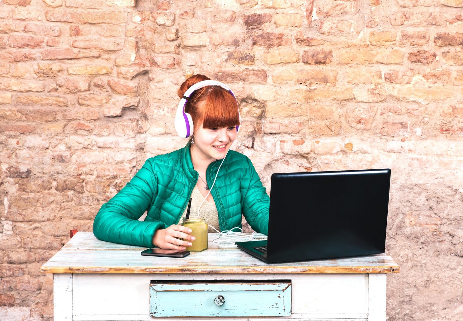 Young woman with headphones using laptop at house office