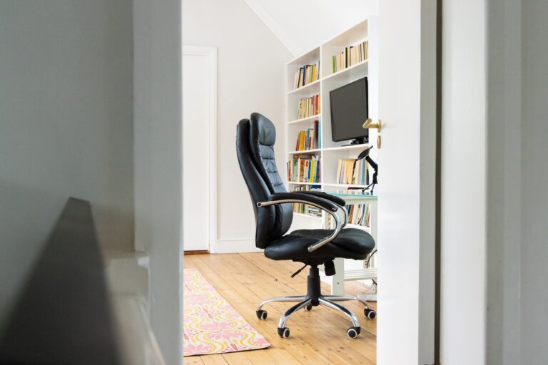 Home office with black chair, bookshelves, and computer, ready for work
