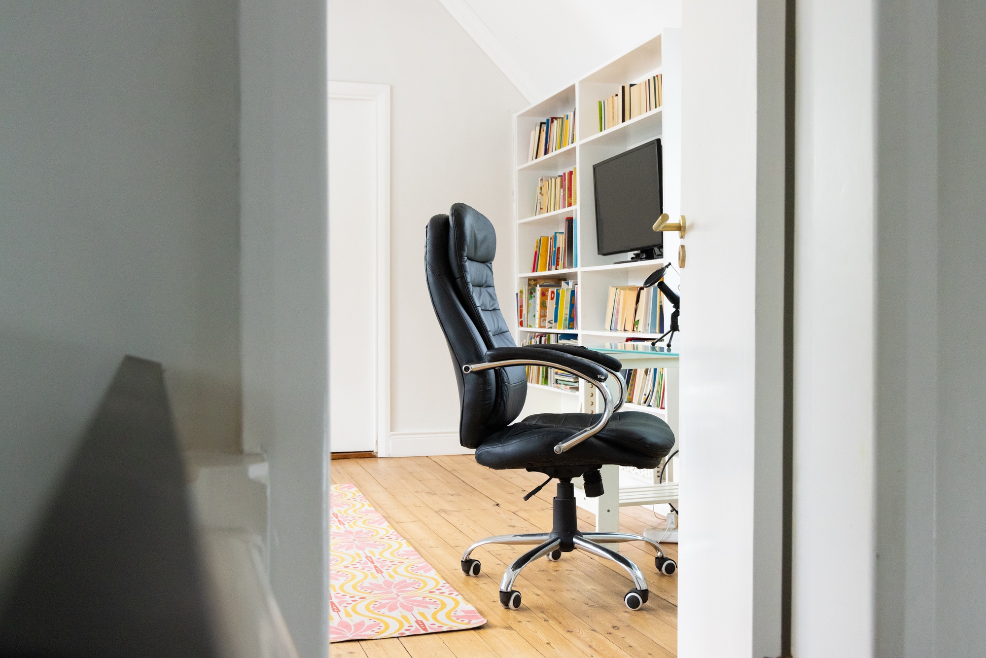 Home office with black chair, bookshelves, and computer, ready for work