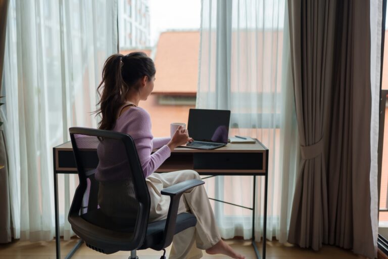 Young woman working remotely from home office enjoying coffee