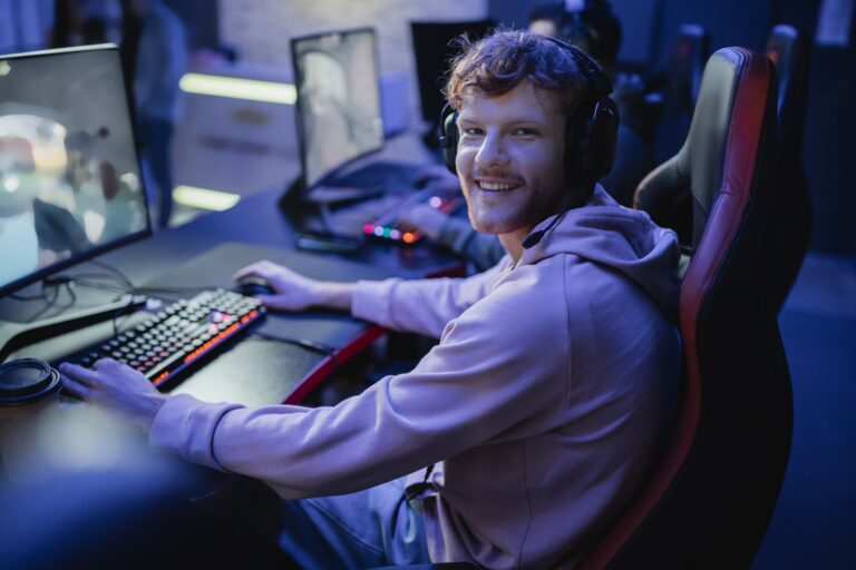 Smiling gamer looking at camera while playing video game in cyber club