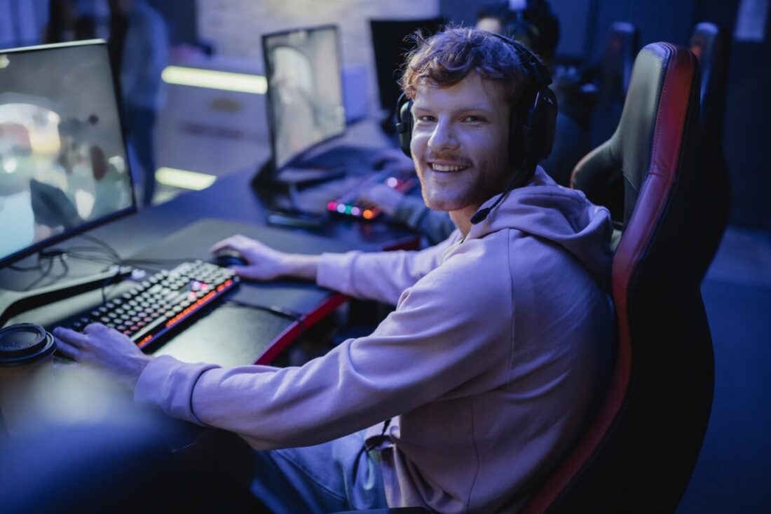 Smiling gamer looking at camera while playing video game in cyber club